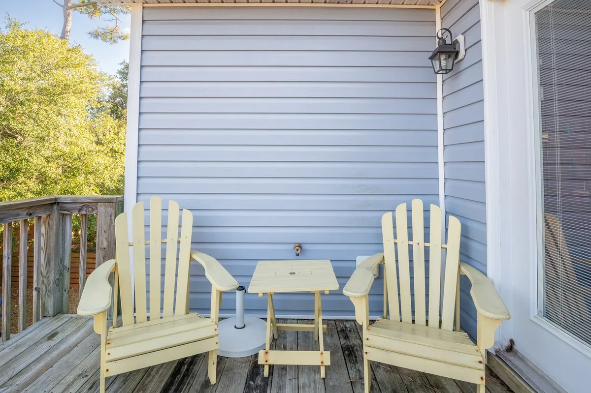 An exterior shot showing yellow Adirondack chairs and a small table on a wooden deck, offering a calm spot for relaxation, conversation, or reading. The outdoor setting underlines the value of shared spaces for group enjoyment beyond the interior.