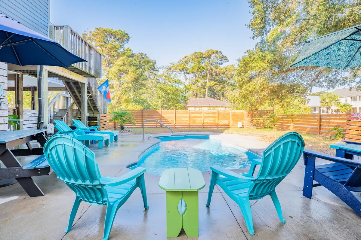 Here, a tranquil pool is bordered by vibrant Adirondack chairs, an umbrella for shade, and lush landscaping. The fenced backyard setting offers both privacy and a secure play space for kids, echoing the section's family-friendly focus.