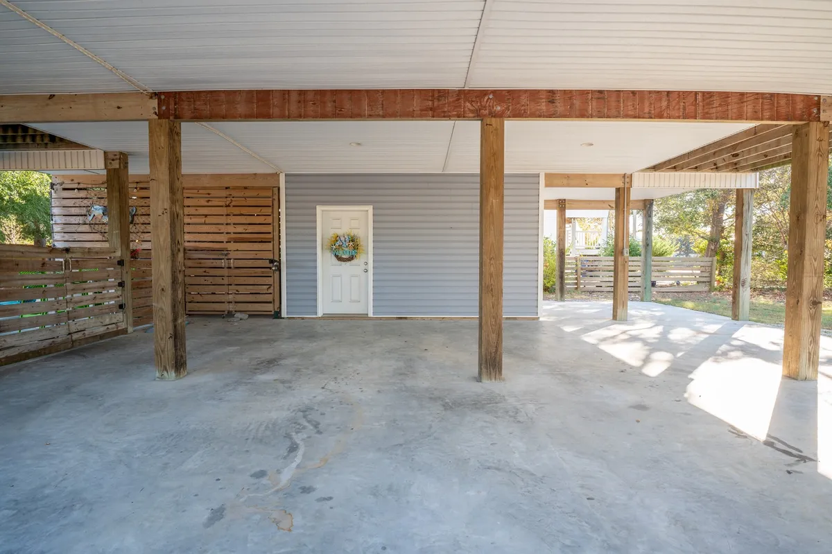 A close-up view of the front door and wooden support beams, adorned with a decorative wreath, evokes a sense of homecoming and group hospitality. The porch area suggests a space for gathering, enjoying meals, or reconnecting during vacations.