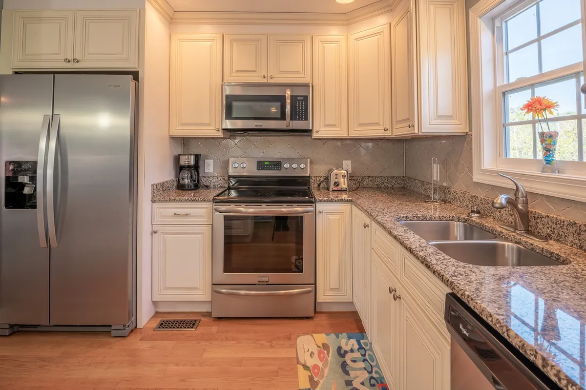 A luxury kitchen featuring stainless steel appliances, gleaming granite countertops, a spacious island with seating, and well-organized kitchen cabinets. The kitchen is perfectly illuminated, creating an inviting space for cooking and gathering.