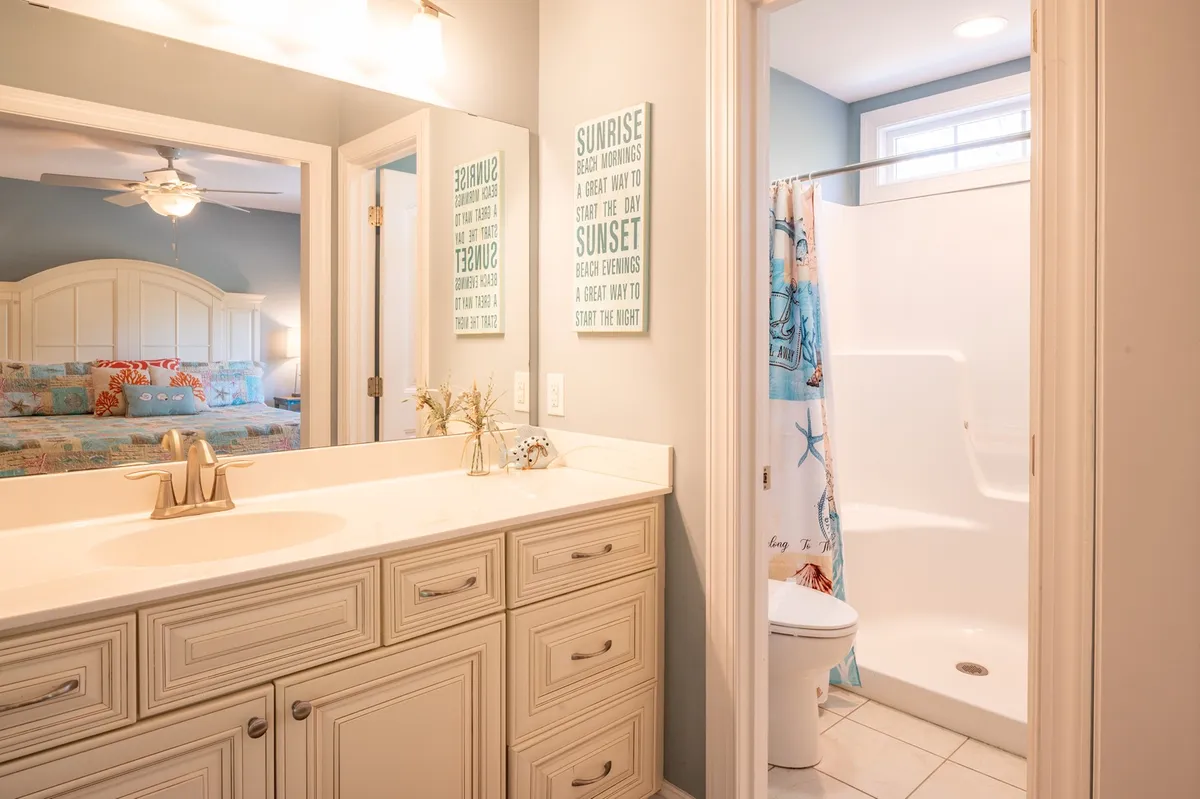 A bright bathroom with a vanity sink, colorful shower curtain, and playful wall décor. The space feels inviting and light, ideal for freshening up after a day outdoors.